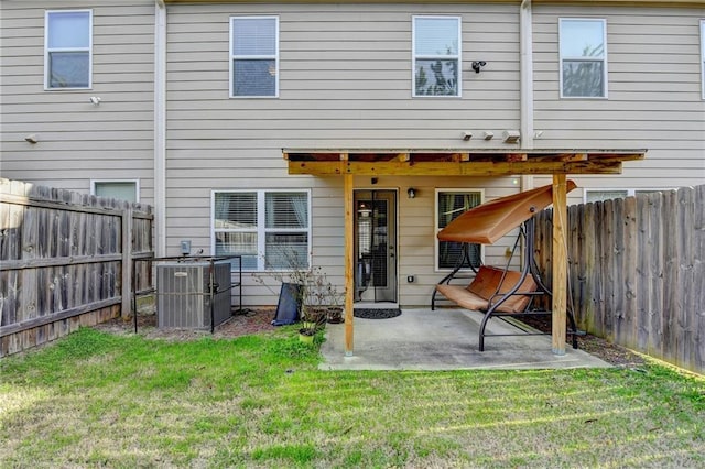 back of house featuring a patio area, a fenced backyard, a lawn, and central AC