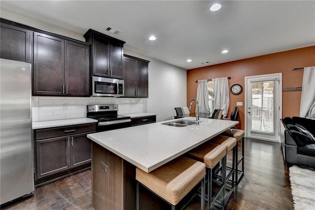 kitchen featuring a sink, stainless steel appliances, light countertops, and a kitchen island with sink