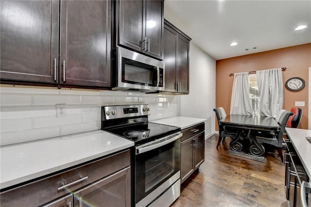 kitchen with appliances with stainless steel finishes, light countertops, dark wood finished floors, and tasteful backsplash