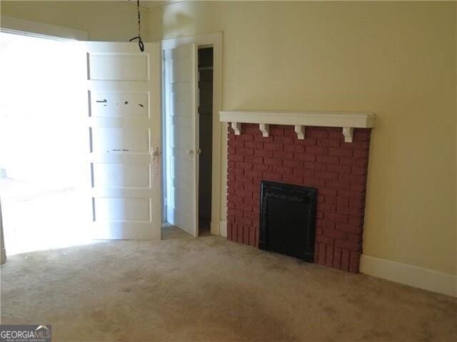 unfurnished living room featuring a brick fireplace and carpet floors