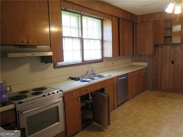 kitchen featuring white range with electric stovetop, wood walls, dishwasher, sink, and ceiling fan