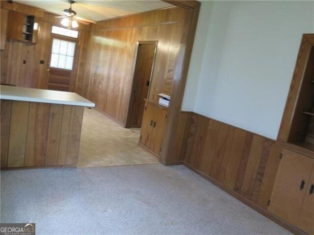 bar featuring ceiling fan, light carpet, and wooden walls