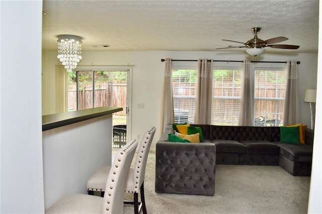 1218 Matt Moore Ct, Lithia Springs, GA 30122 - living room featuring carpet floors, a textured ceiling, visible vents, and ceiling fan with notable chandelier