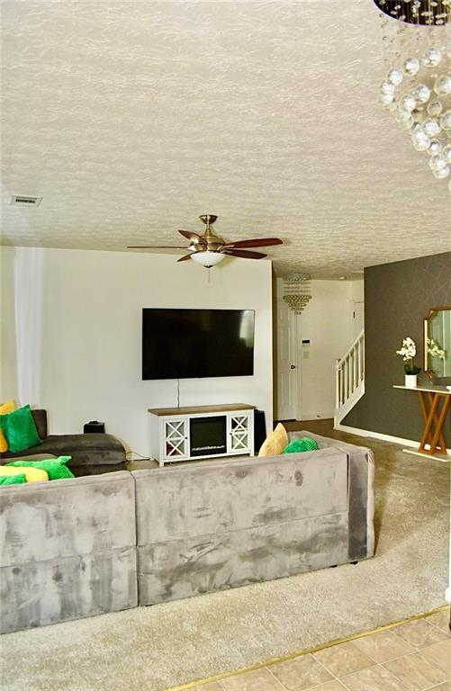 1218 Matt Moore Ct, Lithia Springs, GA 30122 - living area featuring a textured ceiling, stairs, and ceiling fan