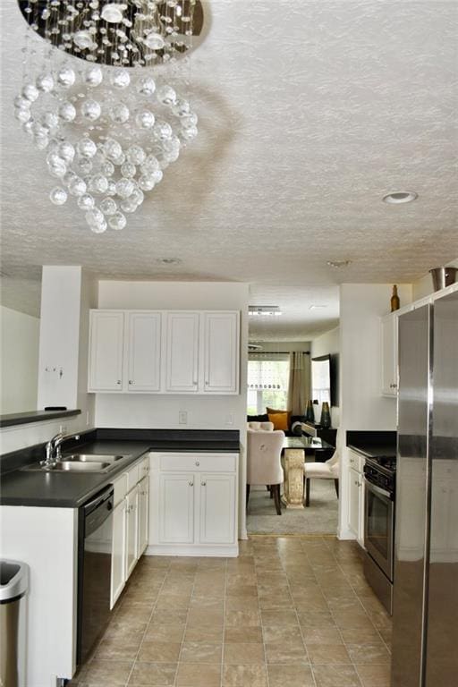 1218 Matt Moore Ct, Lithia Springs, GA 30122 - kitchen featuring a textured ceiling, dark countertops, a sink, stainless steel appliances, and white cabinetry