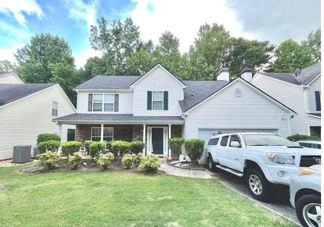 traditional-style house with a chimney, an attached garage, covered porch, cooling unit, and a front yard