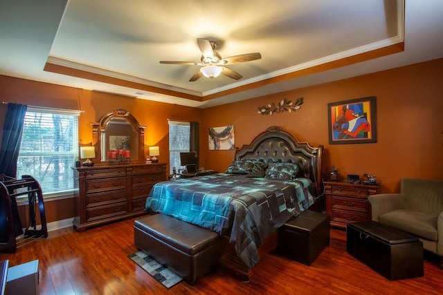 bedroom with a tray ceiling, ornamental molding, dark hardwood / wood-style floors, and ceiling fan