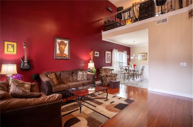 living room with a towering ceiling, ornamental molding, and hardwood / wood-style floors