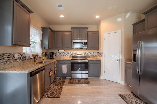 kitchen with sink, gray cabinets, appliances with stainless steel finishes, tasteful backsplash, and light stone countertops