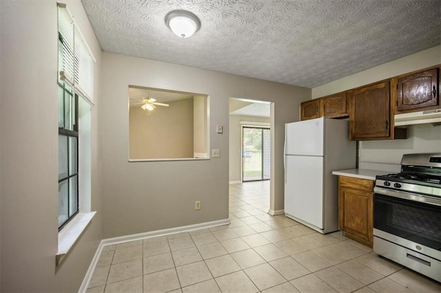 5426 Martins Crossing Rd, Stone Mountain, GA 30088 - kitchen with gas stove, freestanding refrigerator, under cabinet range hood, ceiling fan, and light countertops