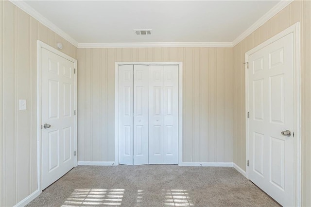 unfurnished bedroom featuring crown molding, light carpet, and a closet