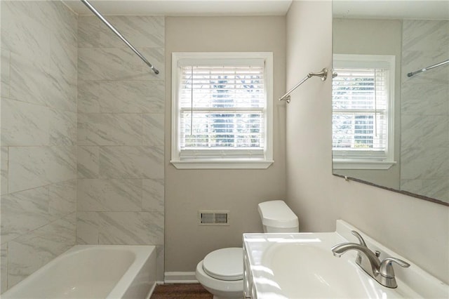 full bathroom featuring a wealth of natural light, sink, tiled shower / bath combo, and toilet