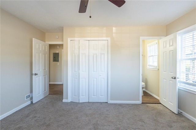 unfurnished bedroom with a closet, light colored carpet, ceiling fan, and electric panel