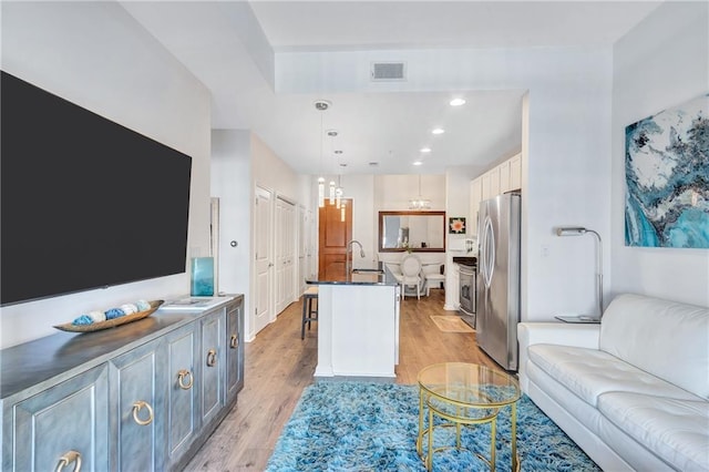 living room with light wood-style flooring, visible vents, and recessed lighting