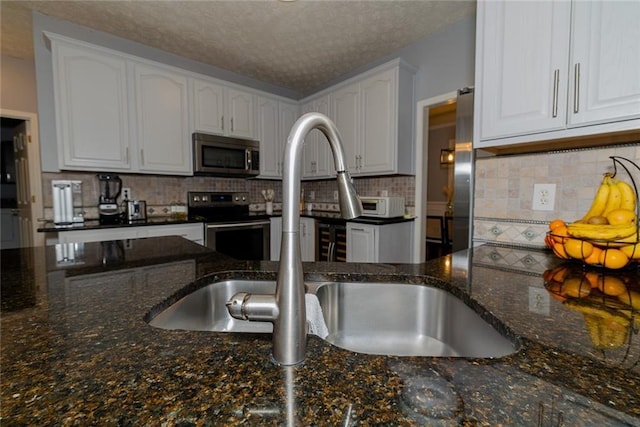 8601 Flint Hill Rd, Douglasville, GA 30135 - kitchen with appliances with stainless steel finishes, white cabinets, dark stone countertops, decorative backsplash, and a textured ceiling