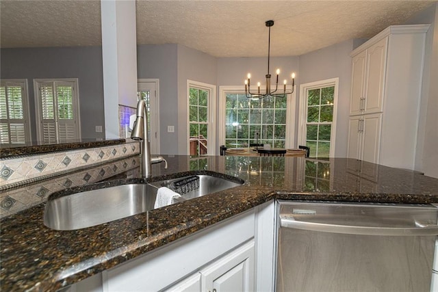 8601 Flint Hill Rd, Douglasville, GA 30135 - kitchen with dishwasher, a sink, a chandelier, white cabinets, and dark stone counters