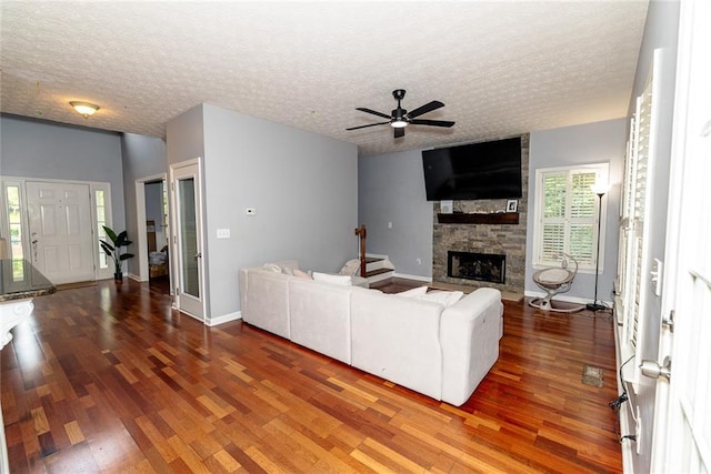 8601 Flint Hill Rd, Douglasville, GA 30135 - living room featuring wood finished floors, ceiling fan, a fireplace, a textured ceiling, and baseboards