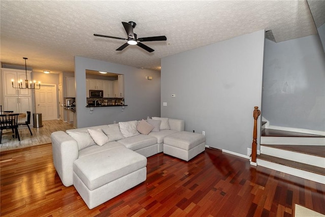 8601 Flint Hill Rd, Douglasville, GA 30135 - living room with wood finished floors, ceiling fan, a chandelier, a textured ceiling, and baseboards