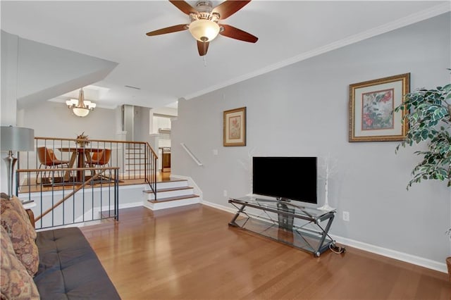 living room with wood-type flooring, ceiling fan with notable chandelier, and ornamental molding