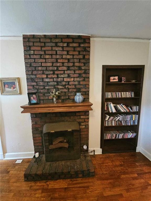 room details featuring ornamental molding, a brick fireplace, a wood stove, and hardwood / wood-style floors