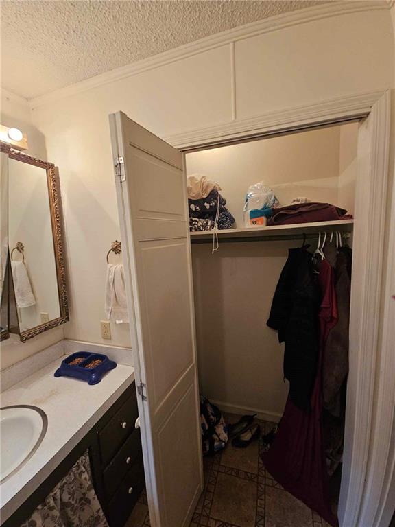 bathroom with tile patterned flooring, a textured ceiling, vanity, and crown molding