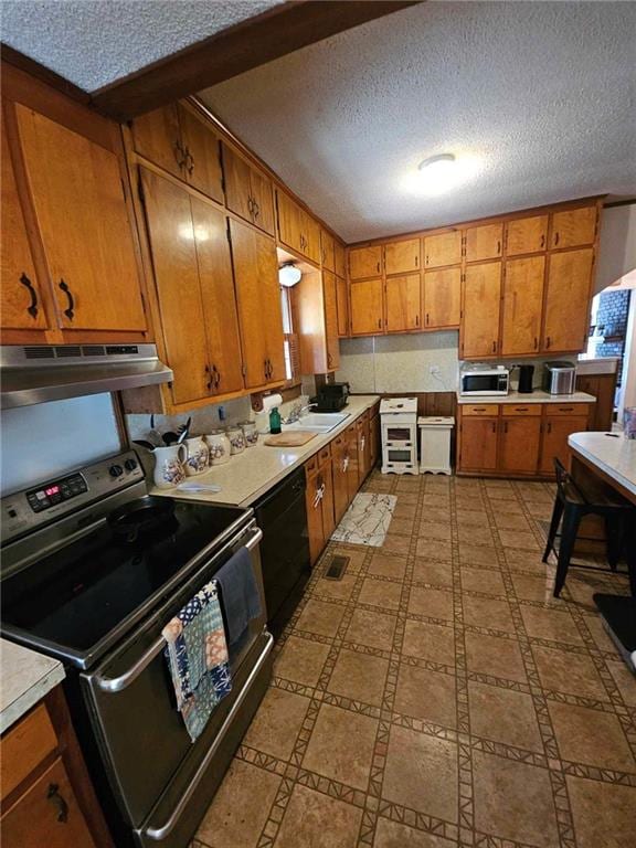 kitchen featuring a textured ceiling, stainless steel appliances, sink, and range hood