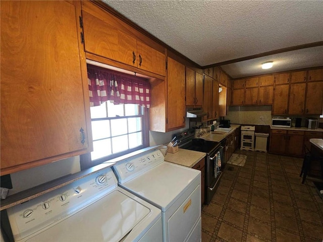 laundry area with a textured ceiling, washing machine and dryer, and wood walls