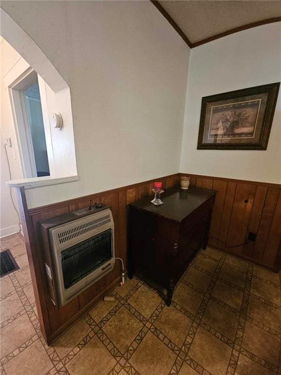 interior space featuring heating unit, wooden walls, and crown molding