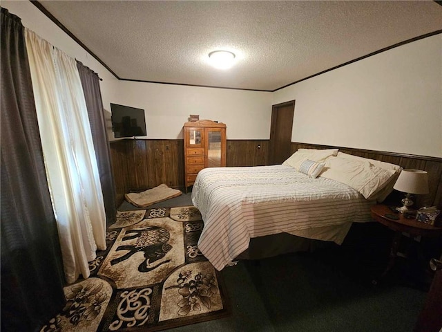 carpeted bedroom with a textured ceiling and wood walls