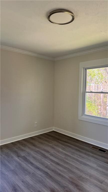 spare room featuring crown molding, baseboards, dark wood-style floors, and visible vents