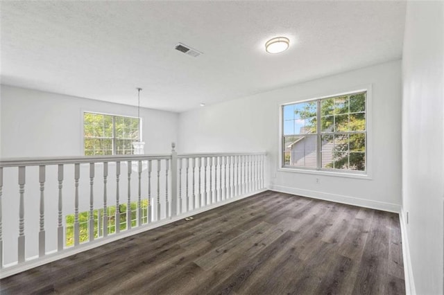 unfurnished room featuring a healthy amount of sunlight and dark hardwood / wood-style flooring