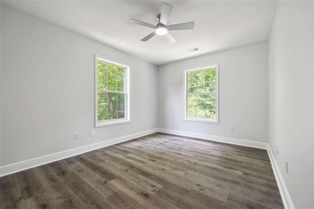 spare room with ceiling fan, plenty of natural light, and dark wood-type flooring