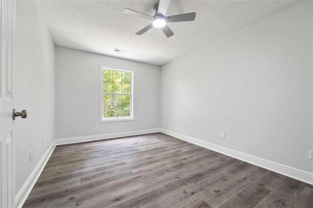 spare room with a textured ceiling, ceiling fan, and dark hardwood / wood-style flooring