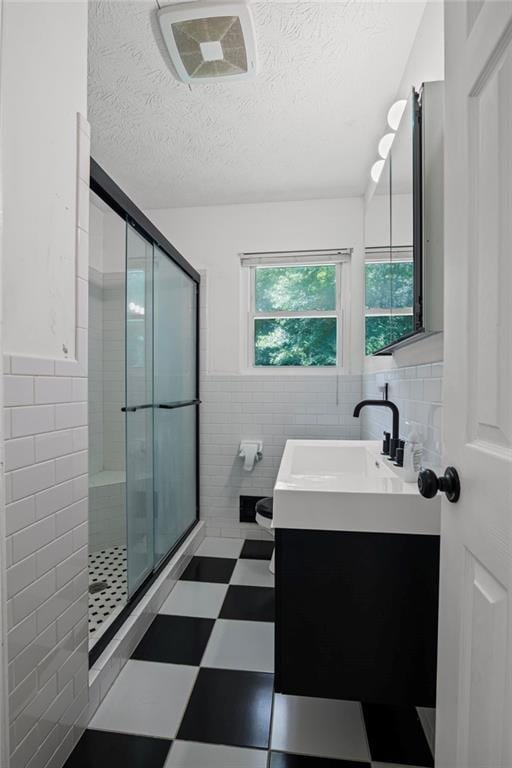4051 Dixie Ln, Douglasville, GA 30135 - bathroom featuring tile walls, vanity, a shower stall, tile patterned floors, and a textured ceiling