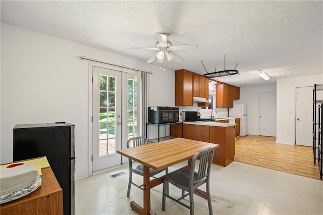 4051 Dixie Ln, Douglasville, GA 30135 - kitchen with black microwave, light flooring, brown cabinets, light countertops, and freestanding refrigerator