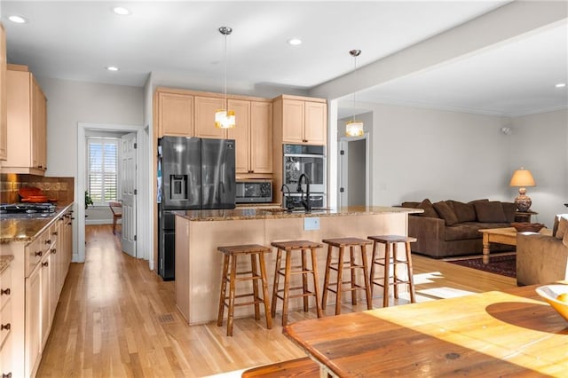 kitchen with light hardwood / wood-style flooring, pendant lighting, a kitchen breakfast bar, and dark stone counters