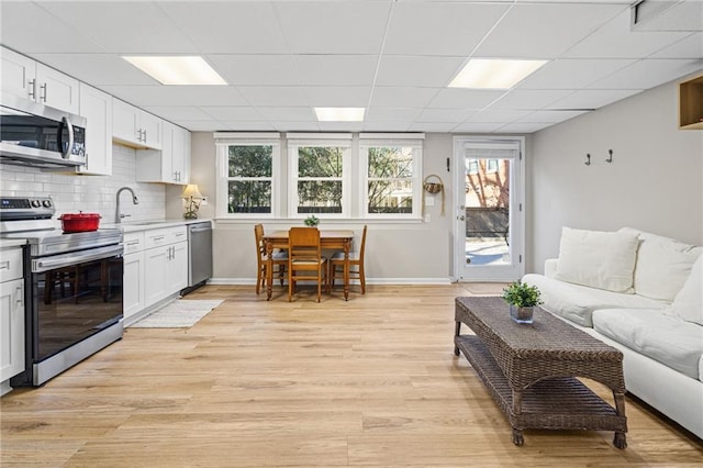 interior space featuring sink, a paneled ceiling, and light wood-type flooring