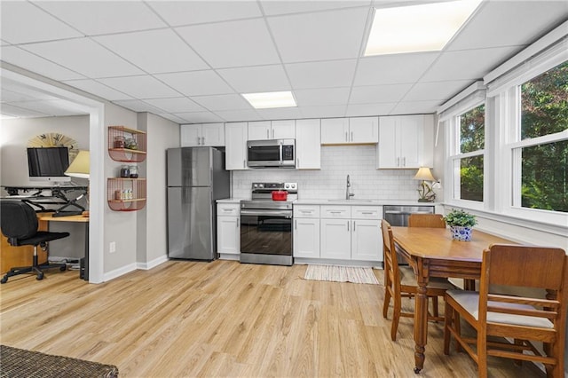 kitchen with sink, white cabinetry, stainless steel appliances, tasteful backsplash, and light wood-type flooring