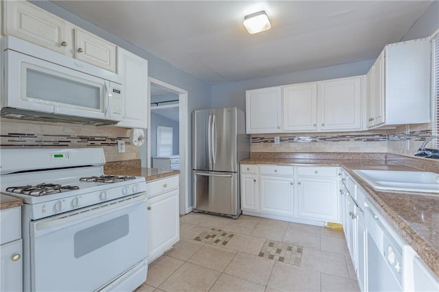 kitchen with white appliances, backsplash, white cabinets, sink, and light tile patterned floors