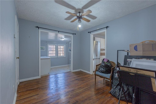 interior space featuring a textured ceiling, ceiling fan, and dark wood-type flooring