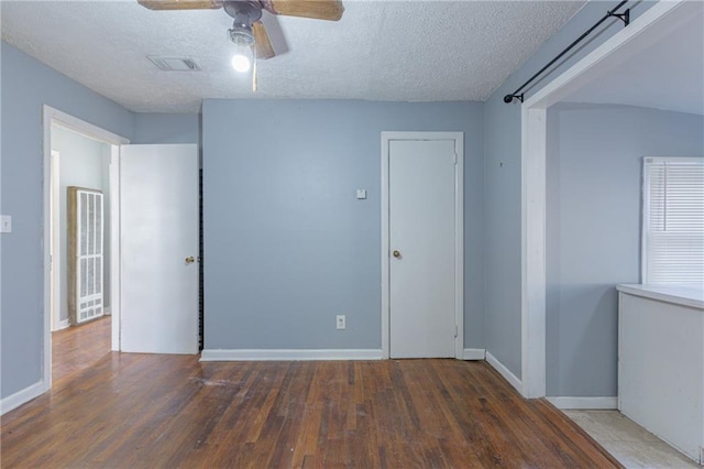 unfurnished room with ceiling fan, dark wood-type flooring, and a textured ceiling