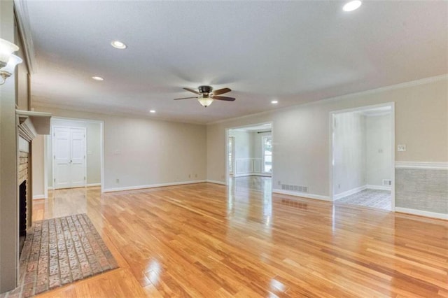 unfurnished living room featuring crown molding, ceiling fan, a fireplace, and light hardwood / wood-style floors