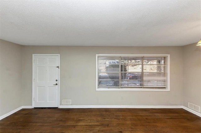 unfurnished room with dark hardwood / wood-style flooring and a textured ceiling