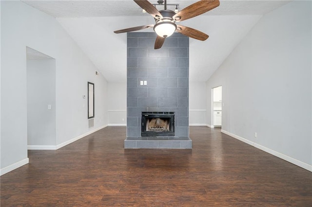 unfurnished living room with dark wood finished floors, a tiled fireplace, and vaulted ceiling