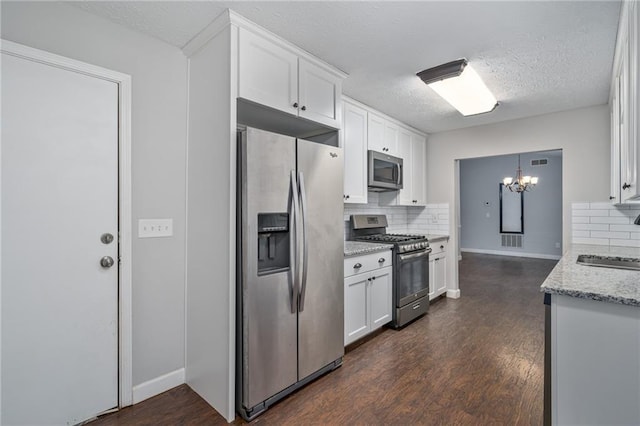 kitchen featuring tasteful backsplash, dark wood-style floors, white cabinetry, stainless steel appliances, and light stone countertops