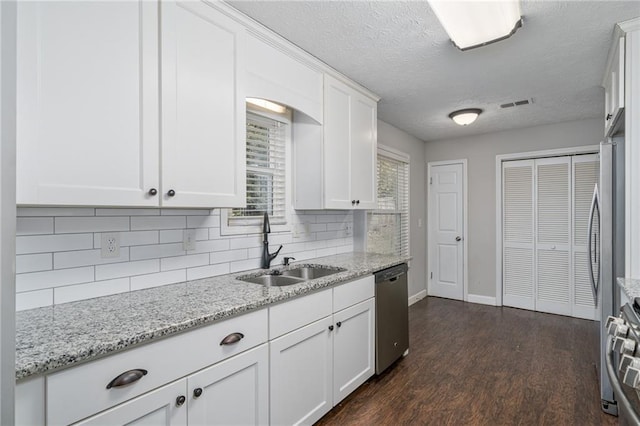 kitchen with visible vents, stainless steel appliances, a sink, dark wood-type flooring, and white cabinets