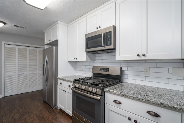 kitchen featuring dark wood finished floors, white cabinets, light stone countertops, and appliances with stainless steel finishes