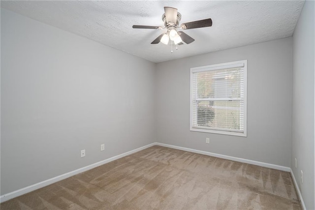 carpeted empty room with a textured ceiling, baseboards, and a ceiling fan