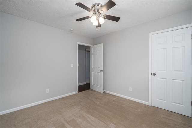 carpeted spare room featuring ceiling fan, baseboards, and a textured ceiling