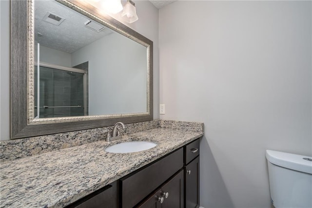 full bathroom with vanity, visible vents, a stall shower, a textured ceiling, and toilet